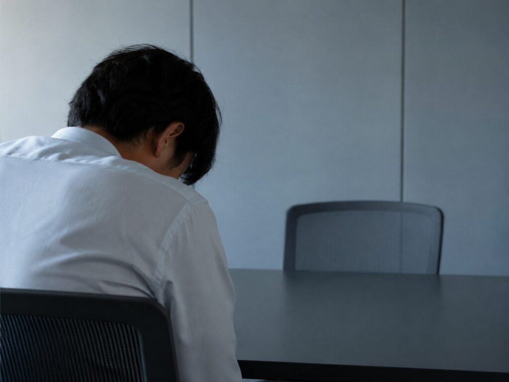 空いた座席とうなだれる男性